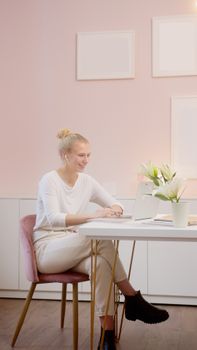 Caucasian woman in cozy home office having a video call on laptop, smiling and relaxed.