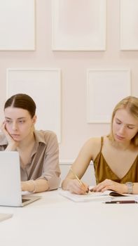 Two women working together at a desk in a modern office setting.