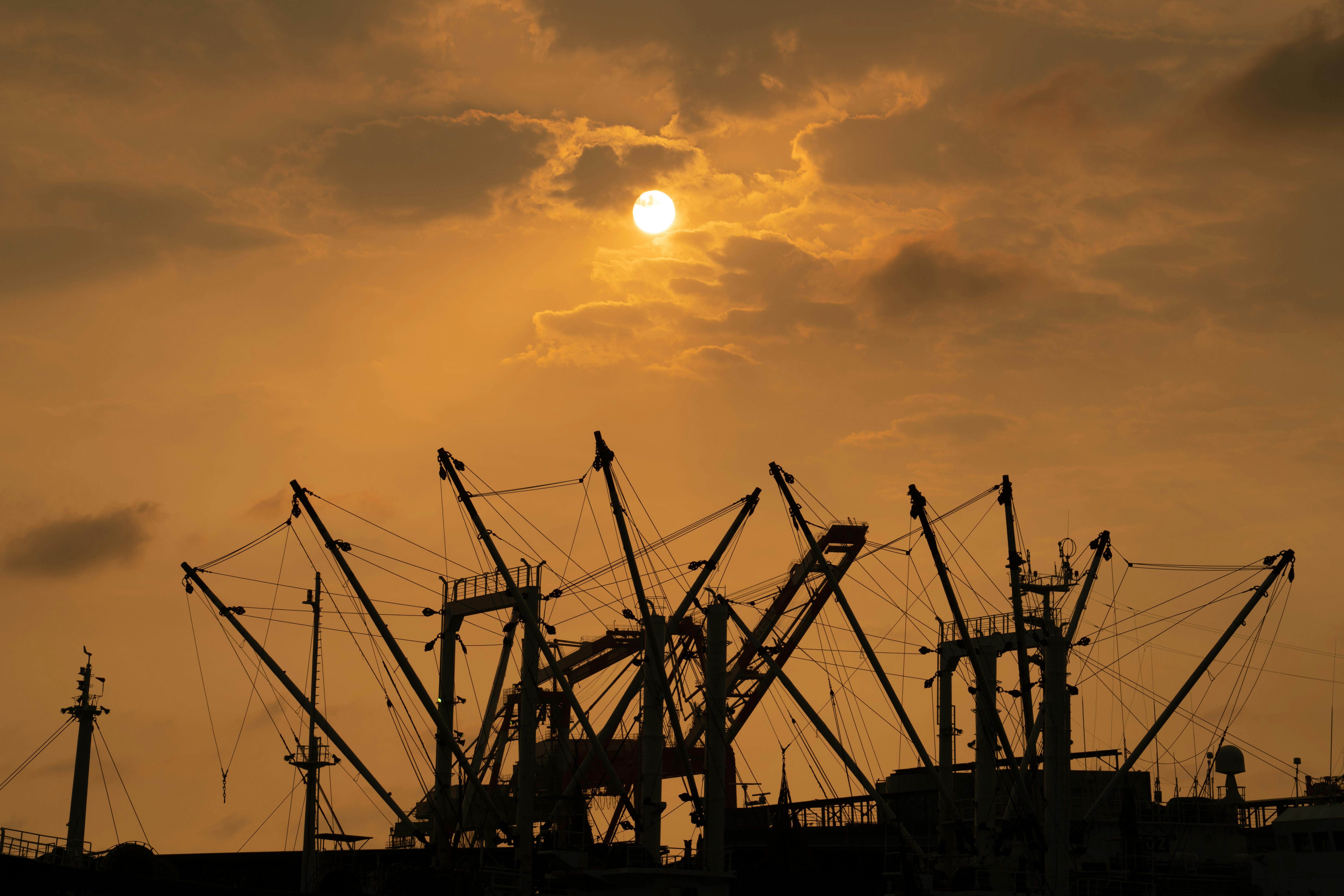 Industrial harbor cranes silhouetted against a warm sunset sky in Taiwan.