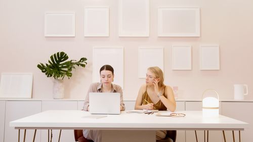 Free Two female colleagues working together on a laptop in a stylish office setting, focusing on teamwork and collaboration. Stock Photo