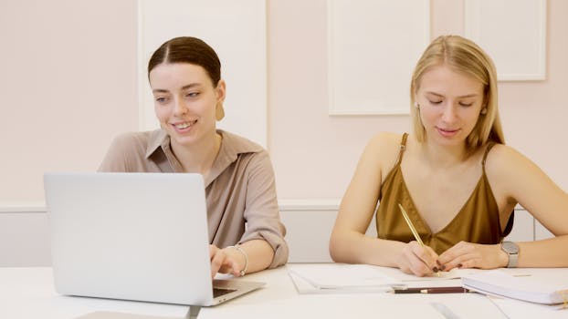 Two women focused on collaborative work in a modern indoor workspace.