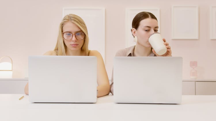 Women Siting In Front Of Laptops On A Table 