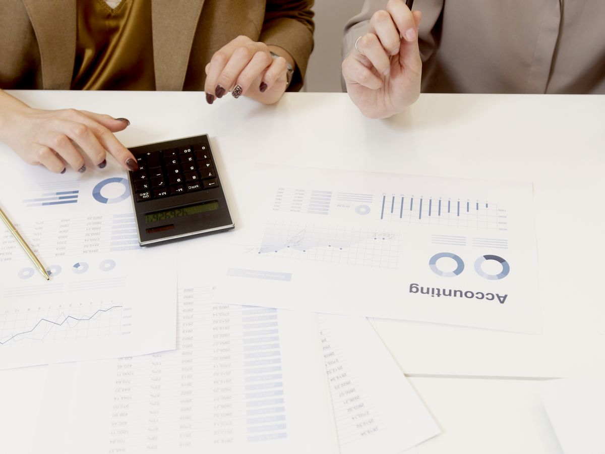 Two professionals analyzing financial documents with a calculator on a table