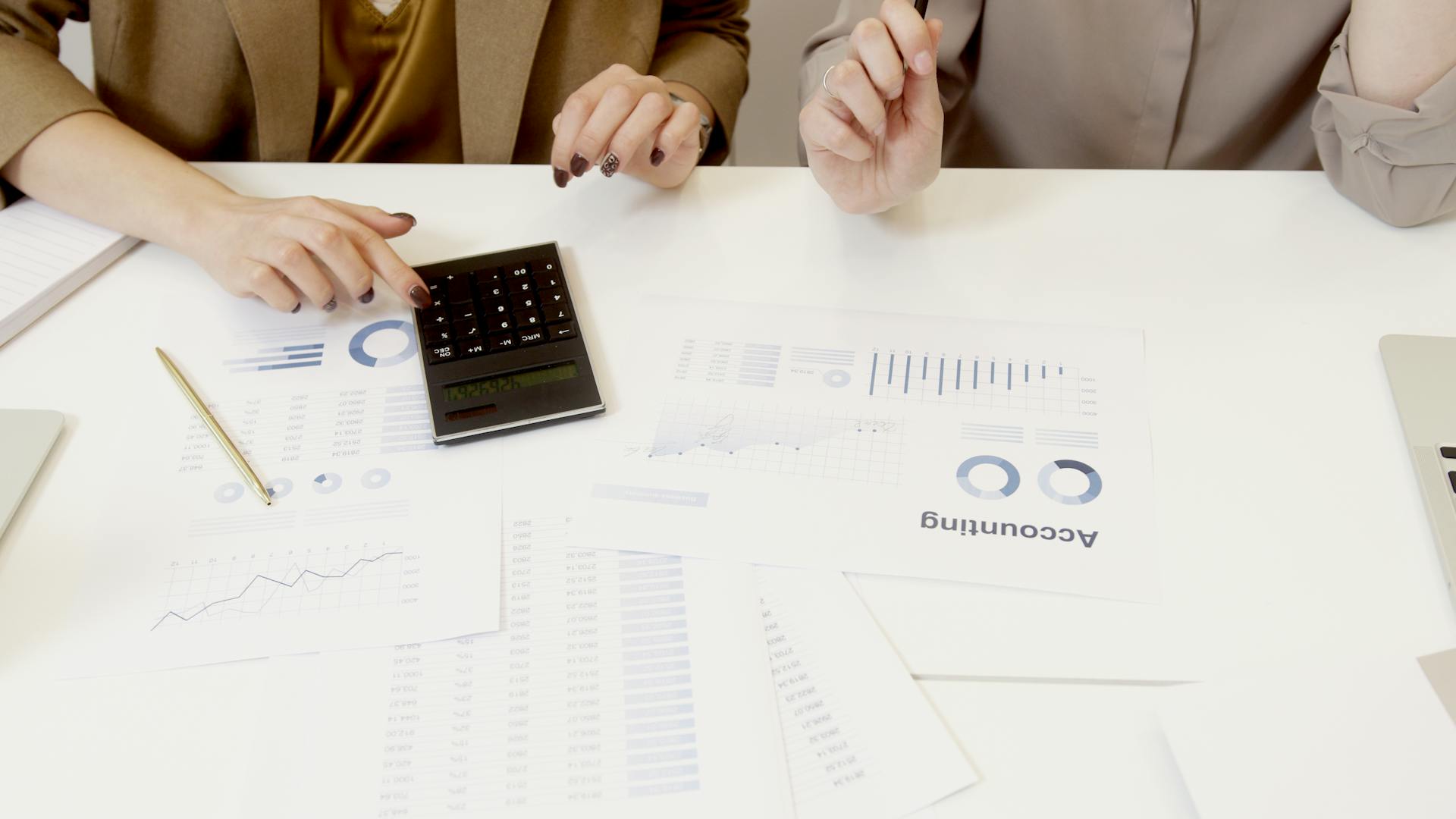 Two professionals analyzing financial documents with a calculator.