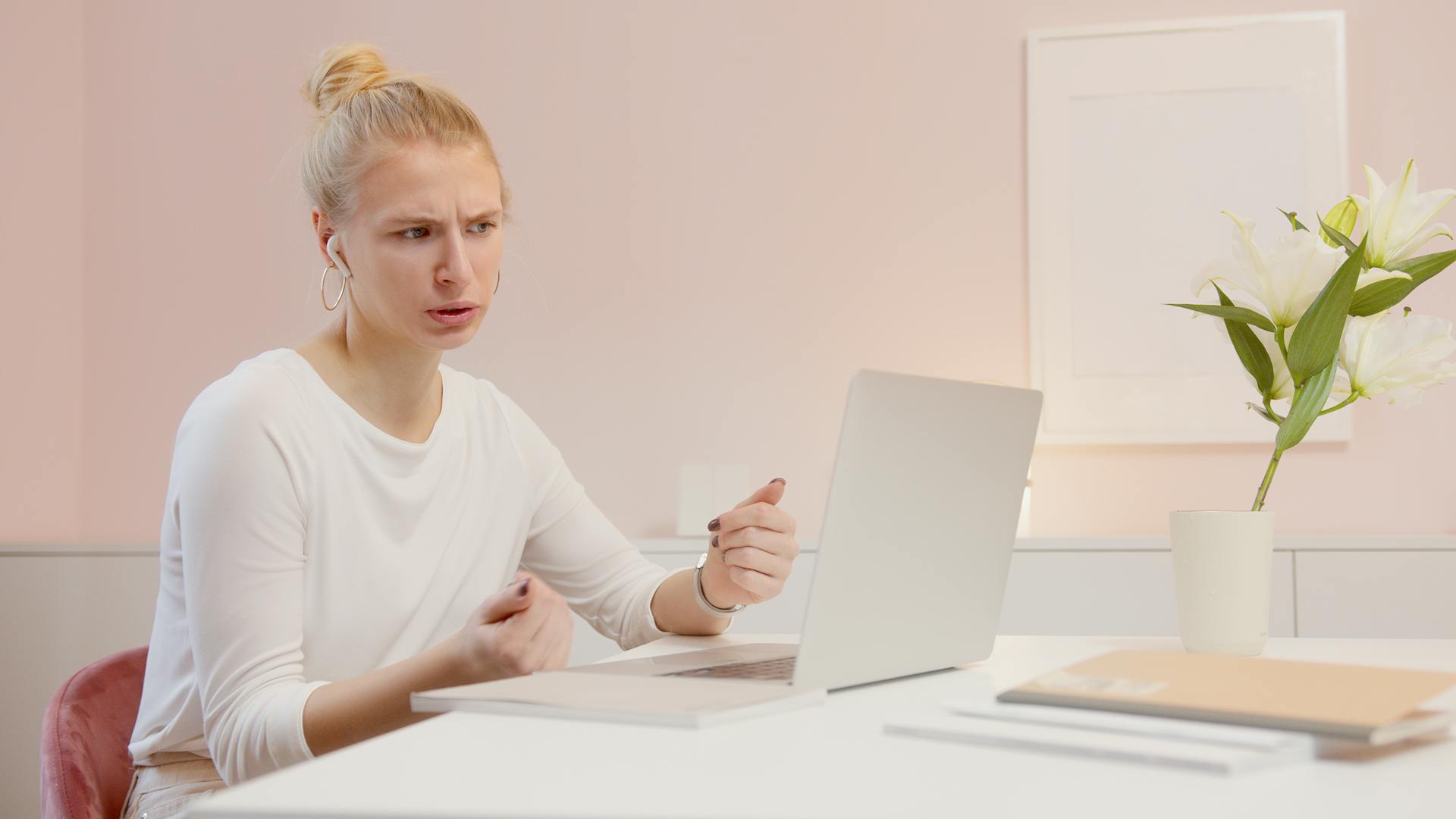 A woman expresses frustration while working at her desk in a modern office setting.