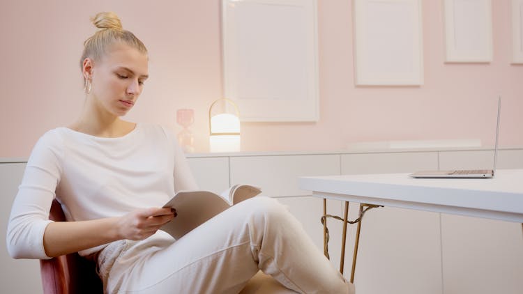 A Woman Sitting On Chair Reading A Book