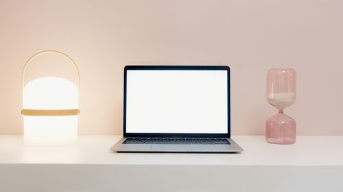 Free A clean minimalist desk setup with a laptop, lamp, and hourglass emphasizes modern design. Stock Photo