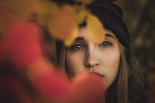 Young woman looking through autumn leaves