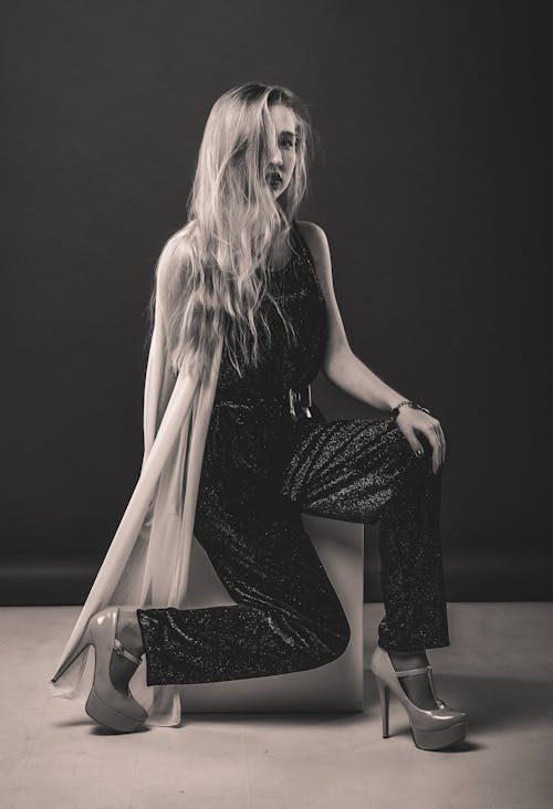 Stylish woman sitting on cube in elegant wear