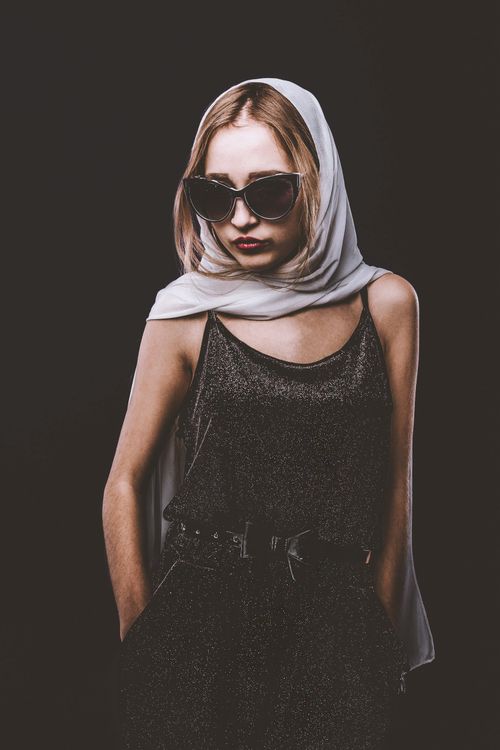 Free Confident trendy female in black velvet outfit and white headscarf standing against black background Stock Photo