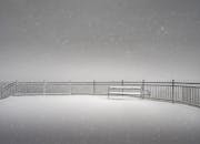 在奥地利雾天的迷人冬季场景中，有一条积雪覆盖的长凳