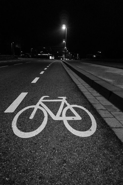 Free Bicycle lane illuminated at night in Aachen, Germany, captured in grayscale for a mysterious urban ambience. Stock Photo