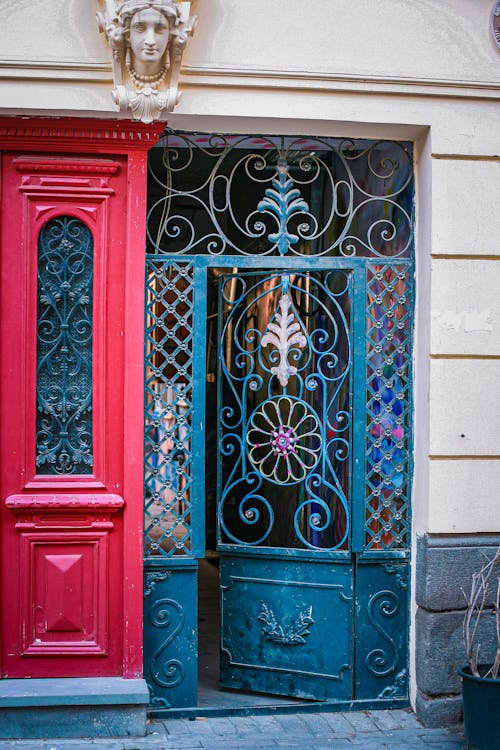 Free Exterior of aged house with ornamental door made of metal with sculpture above entrance in city street Stock Photo