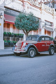 A classic vintage car parked in a charming European street beside a wine gallery.