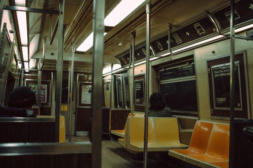 Free People sitting on colorful passenger seats in wagon of metro train with handrails and window during ride in subway station Stock Photo