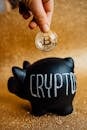Person Putting Bitcoin in a Piggy Bank