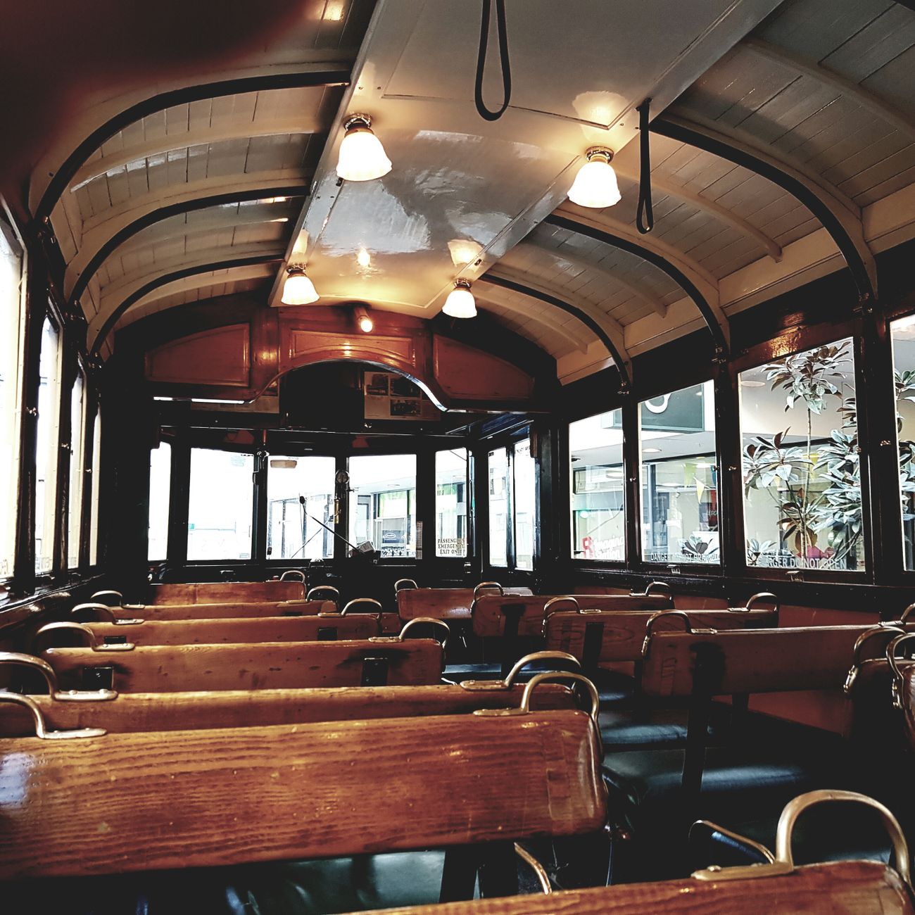 Explore the classic wooden interior design of an empty vintage tram with natural lighting.