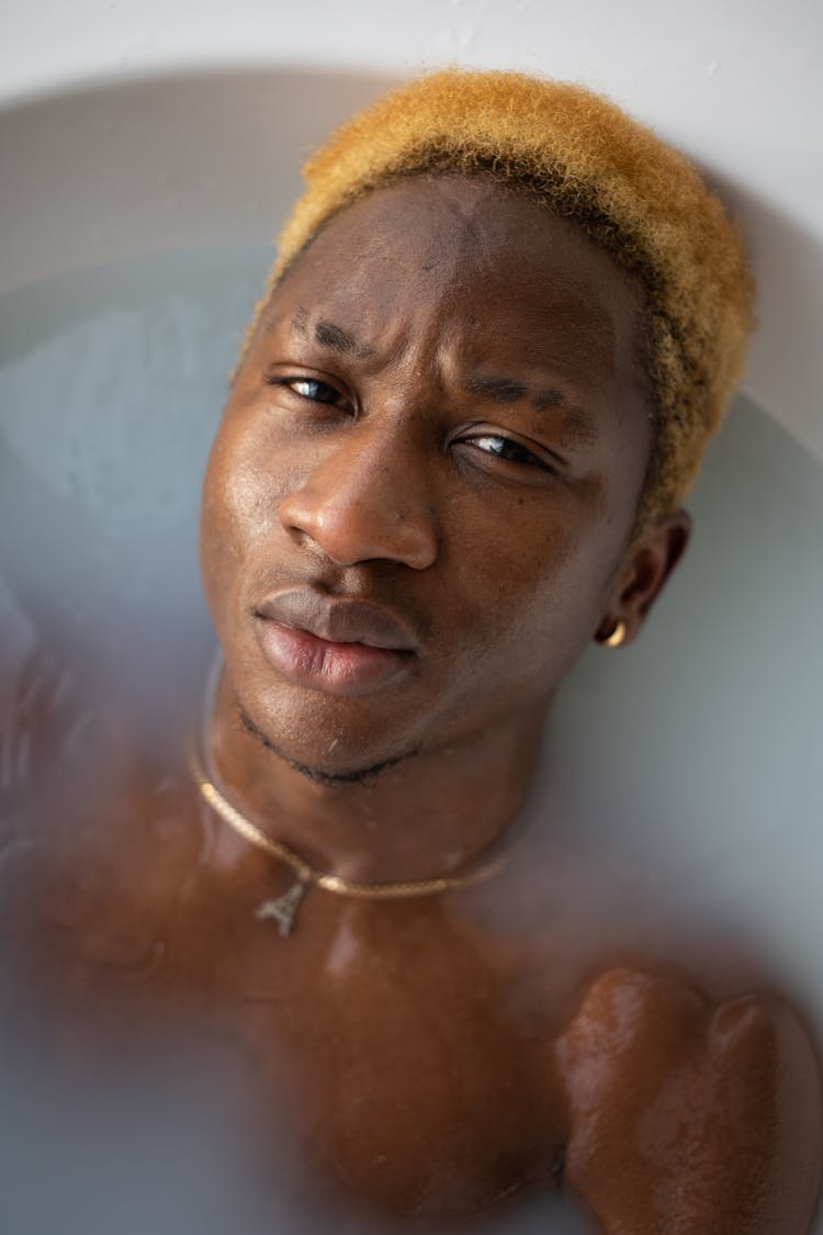 Black Man With Dyed Hair Lying In Bathtub