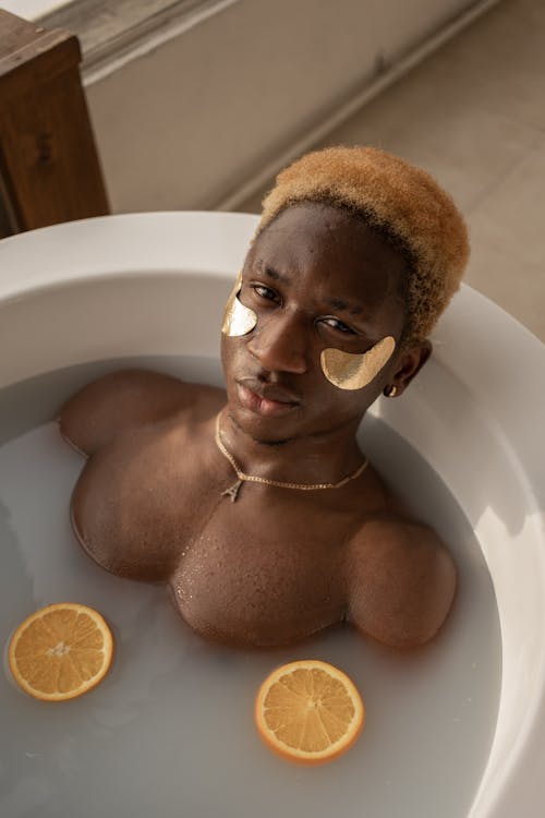 Free From above of African American male with golden patches under eyes looking at camera during spa procedures Stock Photo