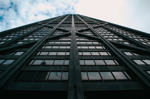 Free An upward perspective of a modern glass skyscraper against a cloudy sky in downtown Chicago. Stock Photo