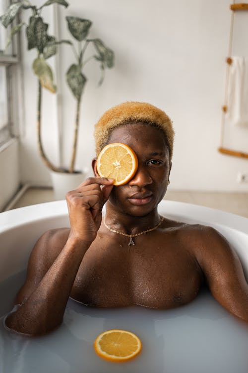 Black man with fresh slice of orange in bath