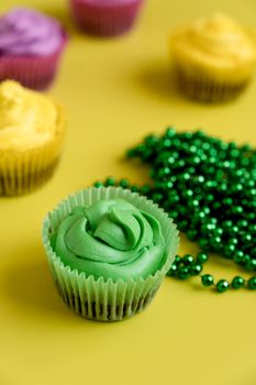 Delicious cupcakes decorated with green, yellow, and purple frosting for Mardi Gras.