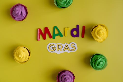 Free Mardi Gras Text And Colorful Cupcakes In Yellow Background Stock Photo