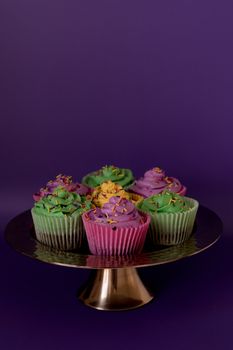 Vibrant Mardi Gras cupcakes with colorful sprinkles on a cake stand.