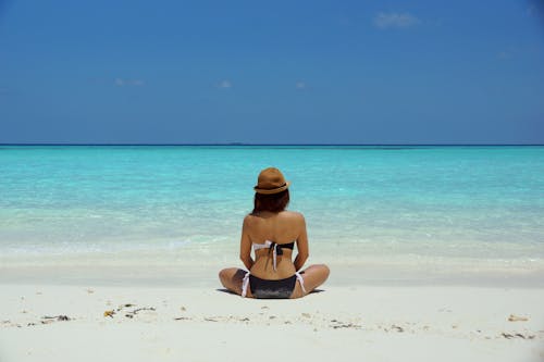 Woman Wearing Black and White Brassiere Sitting on White Sand