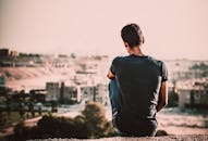 白天，一个人坐在小山上，眺望着城市景观