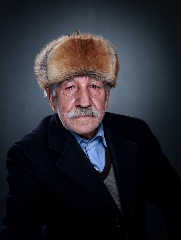 Portrait Of An Old Man In Black Suit With Trapper Hat