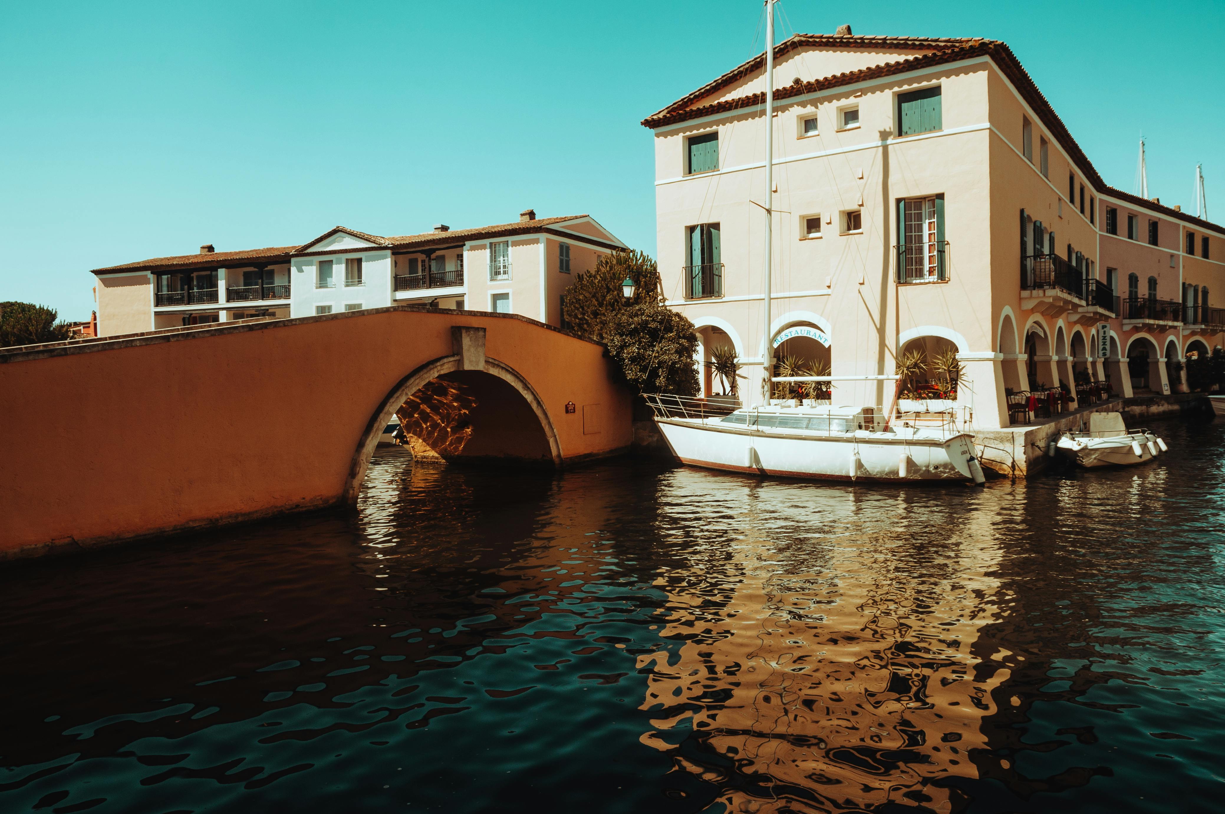Free Elegant buildings by the water in Grimaud, France, with docked boats and reflections. Stock Photo