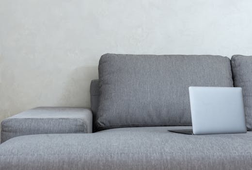 Elegant gray sofa with sleek laptop, showcasing modern minimalist home design.