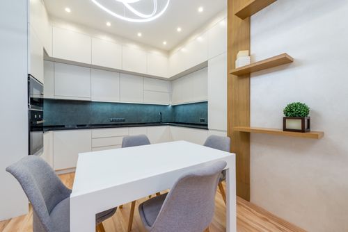 Free Modern apartment interior with table with chairs next to shelves and open kitchen with cabinets Stock Photo