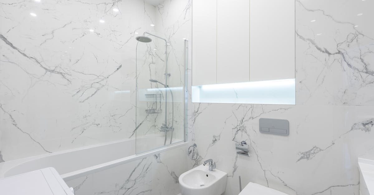 Interior of modern bathroom with toilet and bidet under mirror on white tile next to bathtub with shower