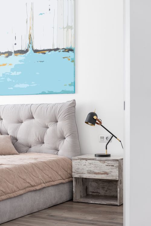 Free Modern bedroom interior with bed with blanket and pillow near table with lamp under painting on wall Stock Photo