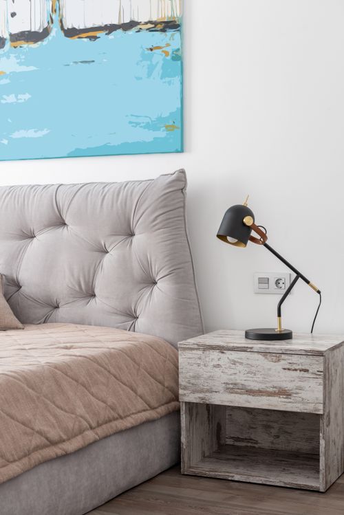 Free Interior of modern light hotel room with bed with blanket near table with lamp and painting on wall Stock Photo