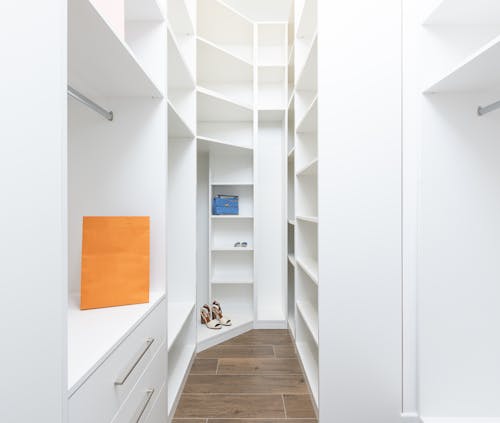 Perspective of white dressing room with rows of shelves and metal railings in modern design