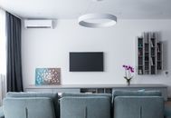Contemporary living room with soft gray sofa and shelves decorating wall in daytime