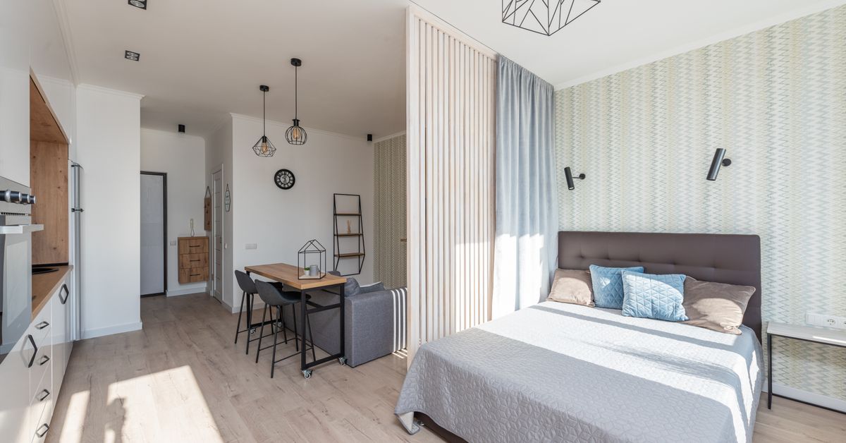 Decoração de Apartamento Pequeno: Ideias para Ganhar Espaço Apartamento pequeno tipo estúdio com cama, sofá e cozinha branca em ambiente integrado e claro