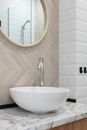 Interior of light modern restroom with sink and faucet on cabinet under mirror on tile wall