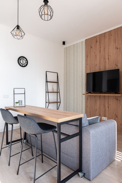 Free Interior of bright modern room with chairs near table next to couch and TV on wall Stock Photo