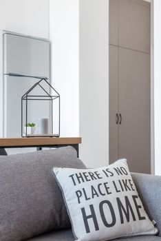 Interior of bright modern room with couch with pillow near table with decorations and fridge next to cabinet