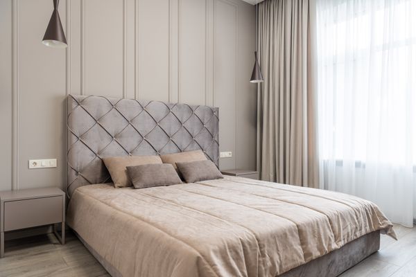 Double room with a buttoned headboard and floor-length curtains. Photo by Max Vakhtbovych on Pexels.