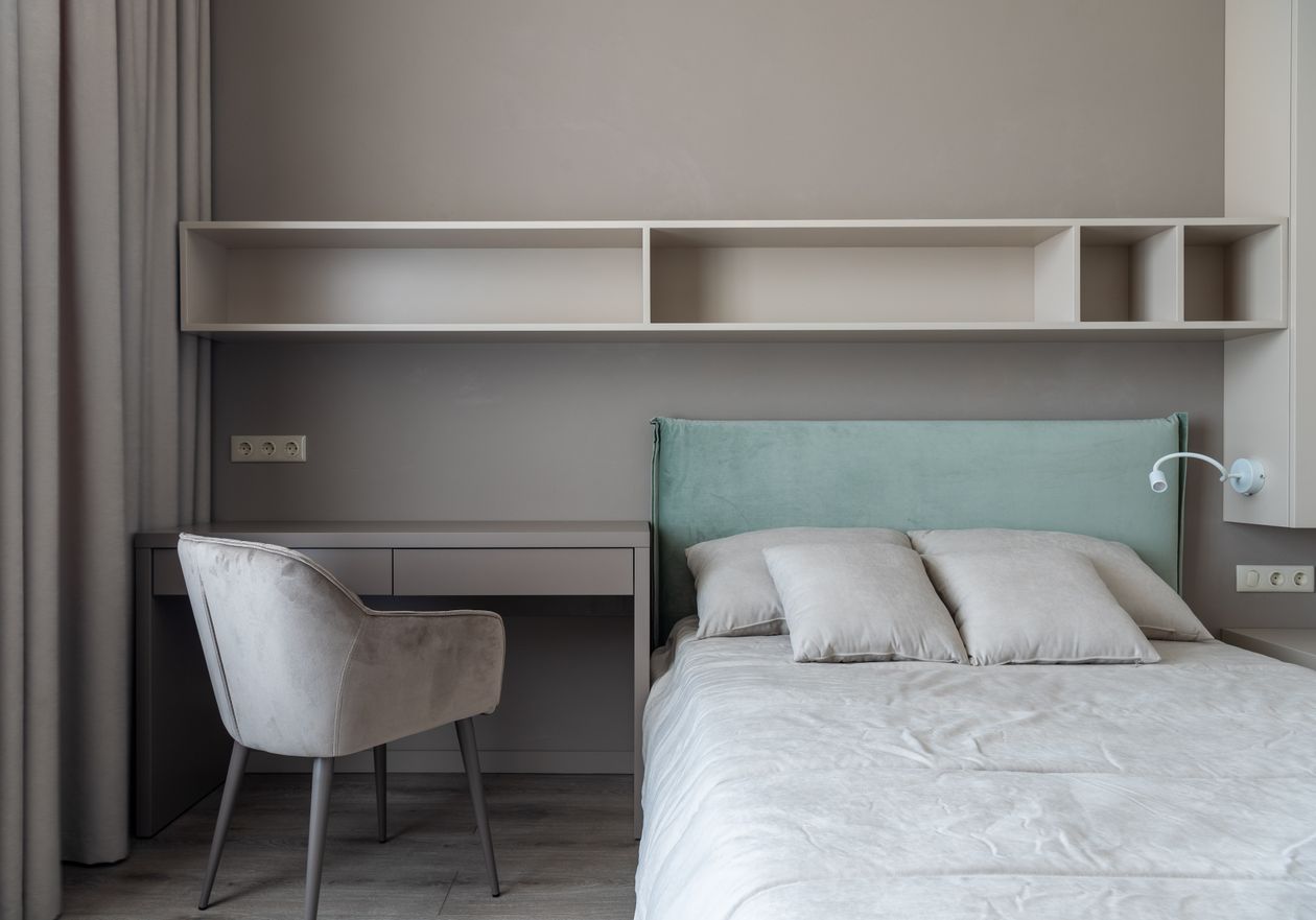 Vertical wall shelves holding books and baskets in a small bedroom.