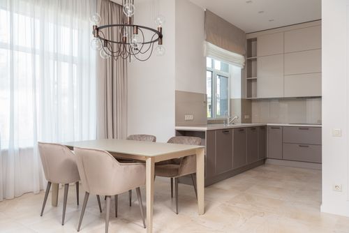Free Interior of bright modern kitchen with cupboards next to window and curtains near chairs with table under chandelier Stock Photo
