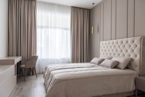 Free Interior of modern light bedroom with pillows on bed near table with chair next to windows with curtains Stock Photo