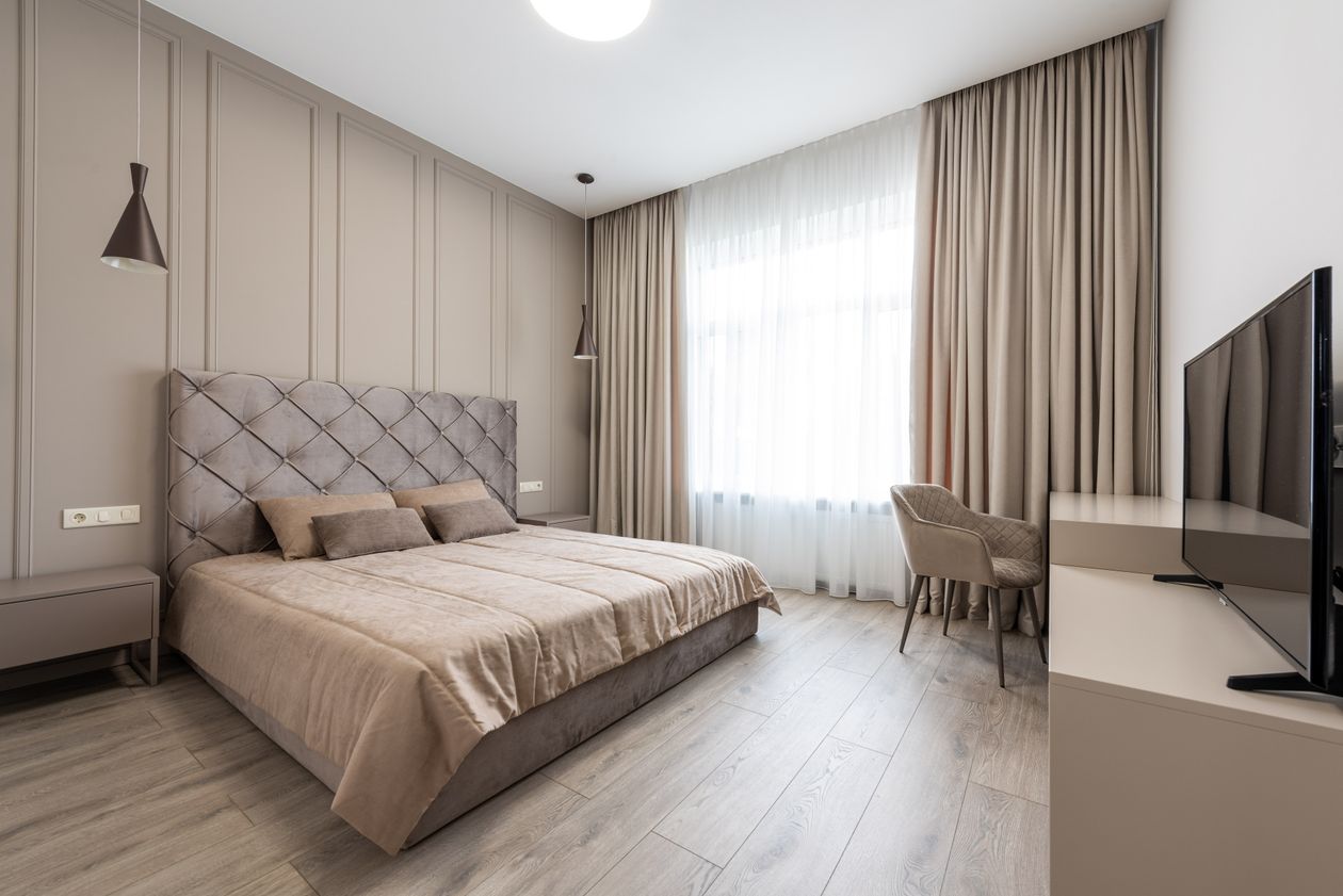 Beige bedroom with a king bed on wood flooring