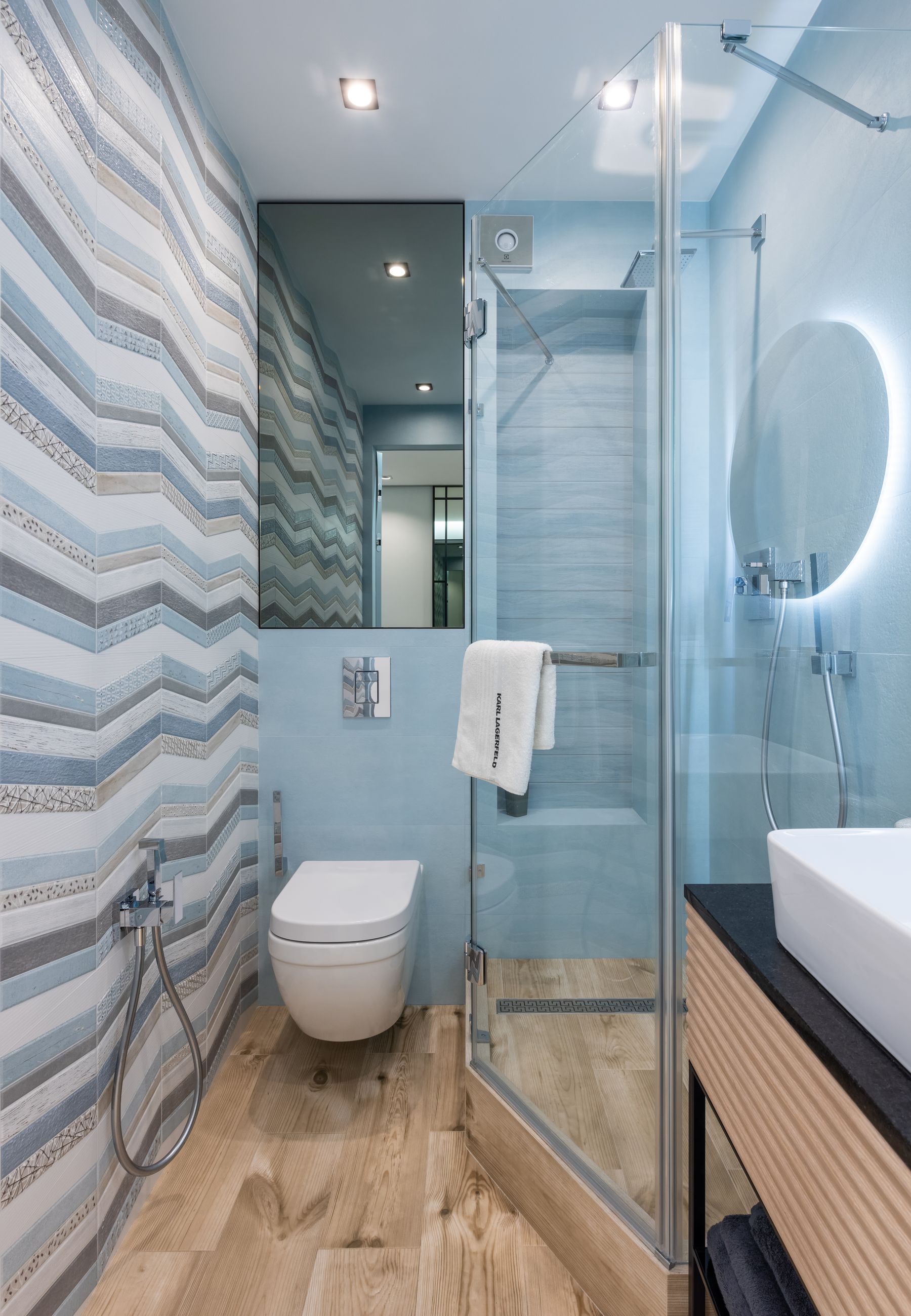 Compact bathroom with a glass shower, toilet and patterned floor tile