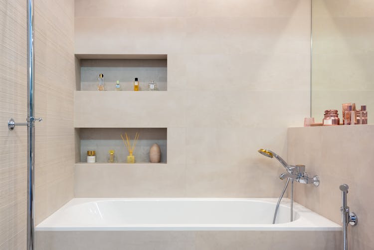 Bathroom Interior With Bathtub With Shower Under Shelves